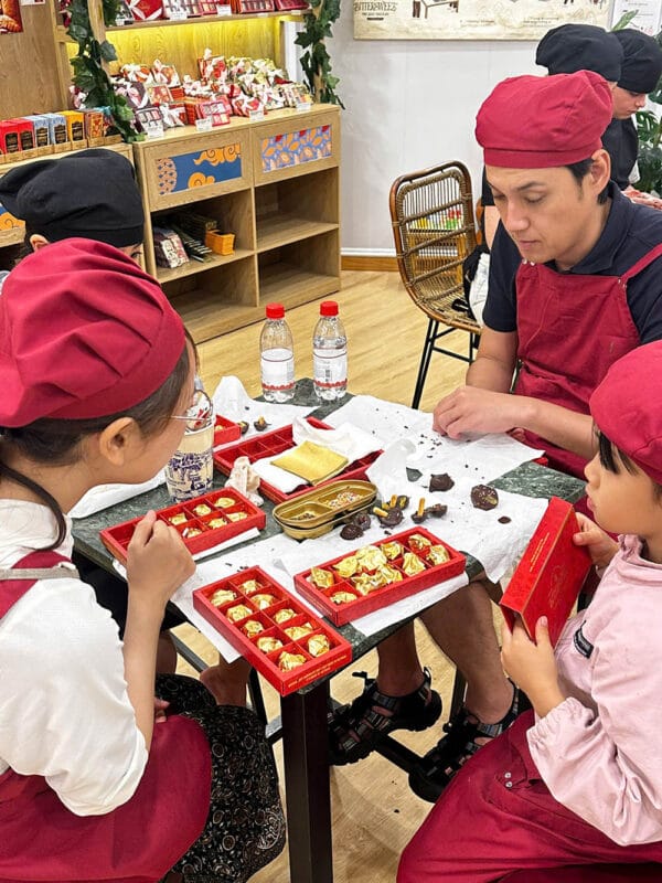 Young participants decorate their own chocolates with guidance during a hands-on workshop at Bittersweet Chocolatier.